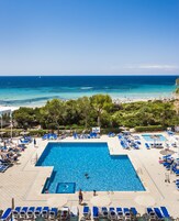 Una piscina al aire libre, sombrillas, sillones reclinables de piscina