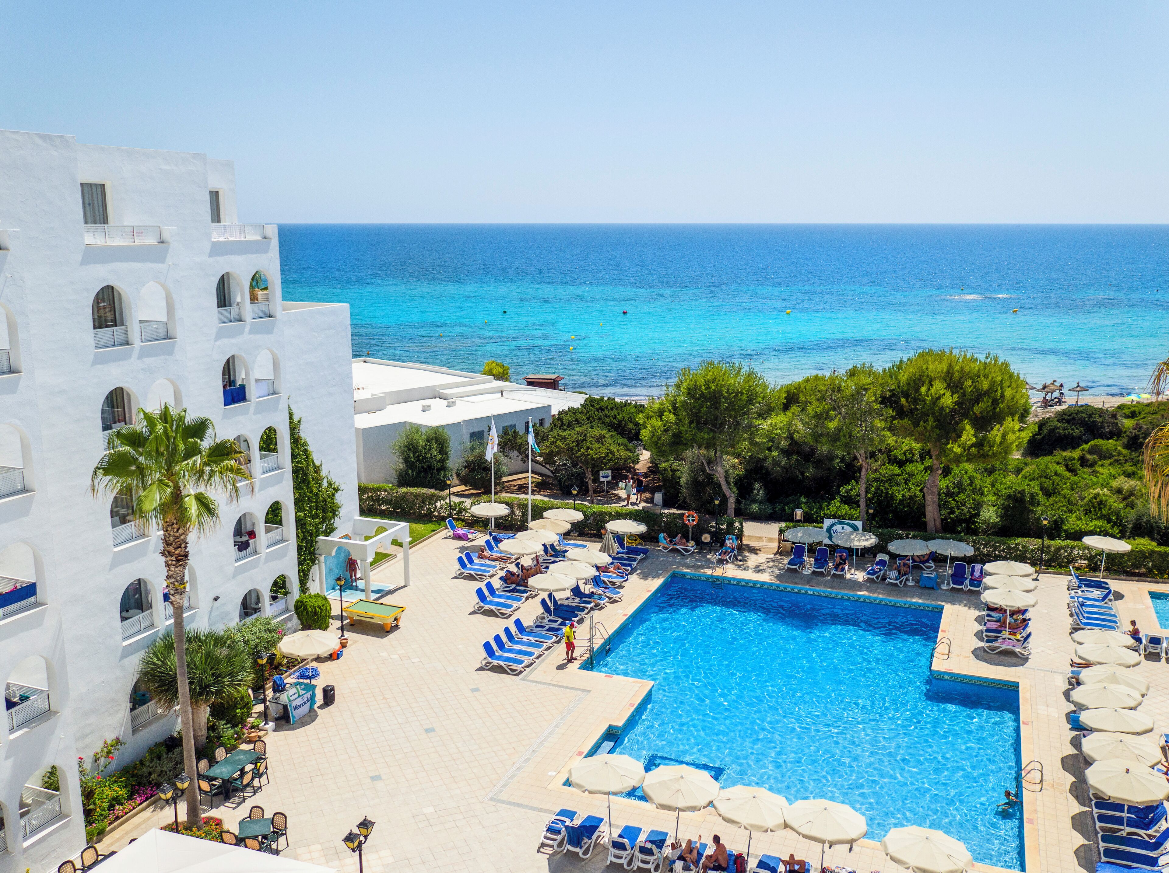 Una piscina al aire libre, sombrillas, tumbonas
