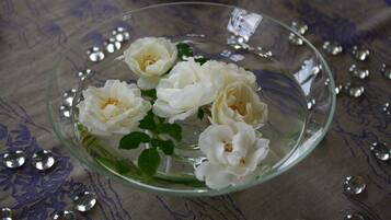 Un cuenco de vidrio transparente con flores blancas y agua sobre una superficie con estampado.