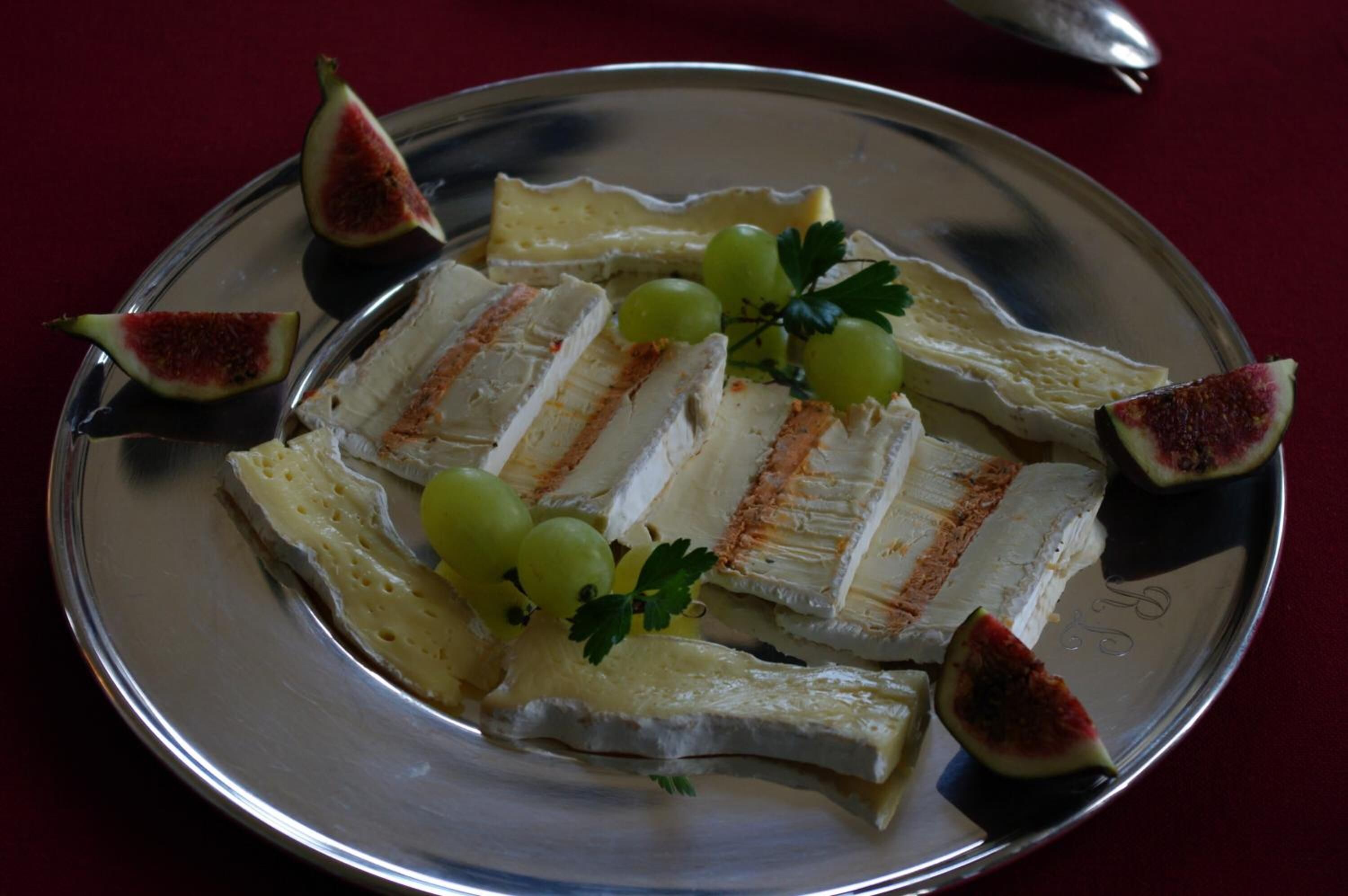 Una bandeja plateada con queso, higos y uvas.