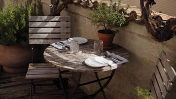 A wooden table set with plates, cutlery, and glasses, surrounded by benches and a potted plant.