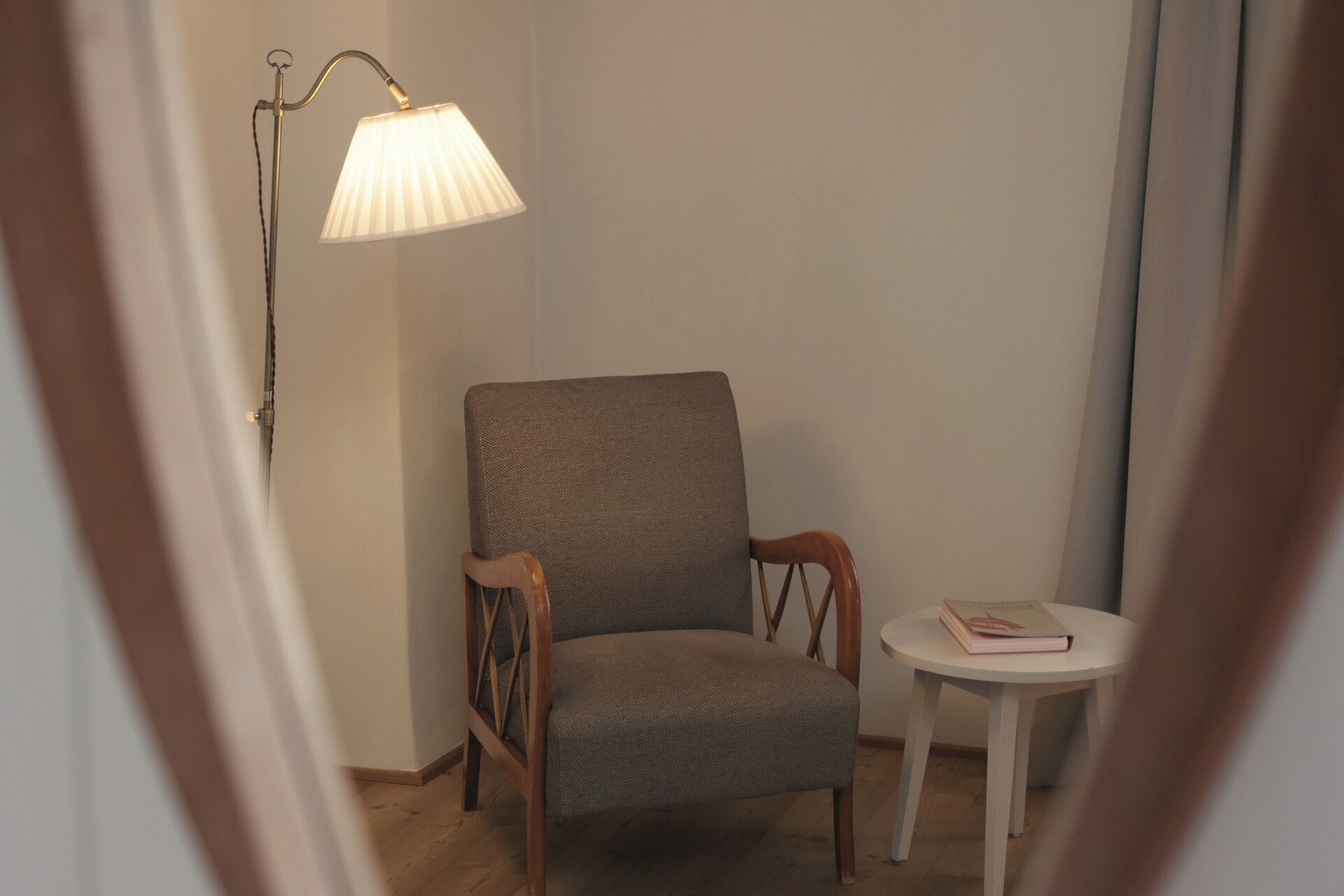 A chair and a small table in a corner of a room with a lamp.