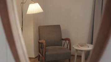 A chair and a small table in a corner of a room with a lamp.