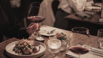 A dining table with a plate of food, a wine glass, and a candle.