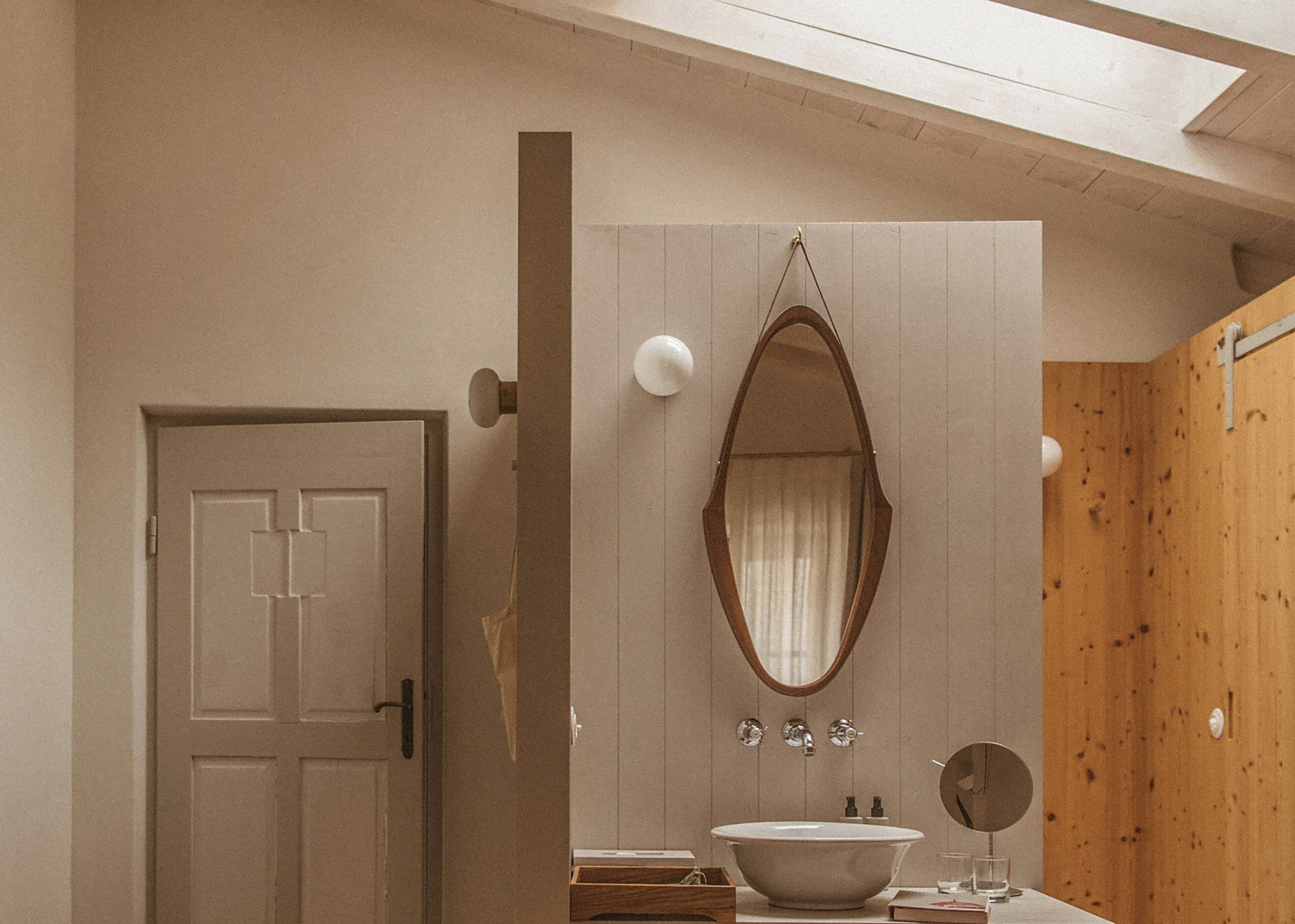 Ein modernes Badezimmer mit einer freistehenden Badewanne, einem großen Spiegel und einer Holzwand.