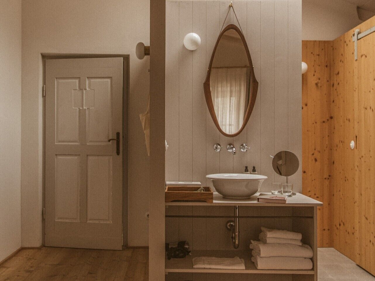 A bathroom with a wooden door, a white sink with a mirror, and a towel rack.