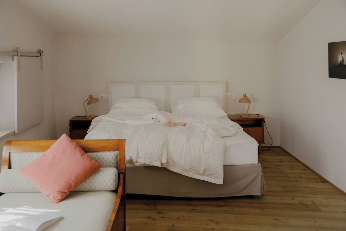 A bedroom with a bed, bedside tables, a chair, and a wooden floor.
