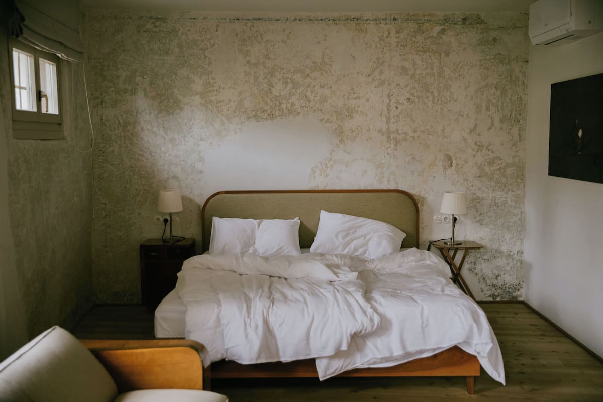 A bedroom with a wooden bed, two bedside tables with lamps, a chair, and a window.