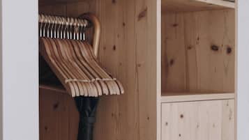 Un armario de madera con una barra para colgar y un objeto enrollado en la parte superior.
