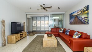 Ein modernes Wohnzimmer mit einem roten Sofa, einem Holztisch und einem Fernseher auf einem Holzständer.