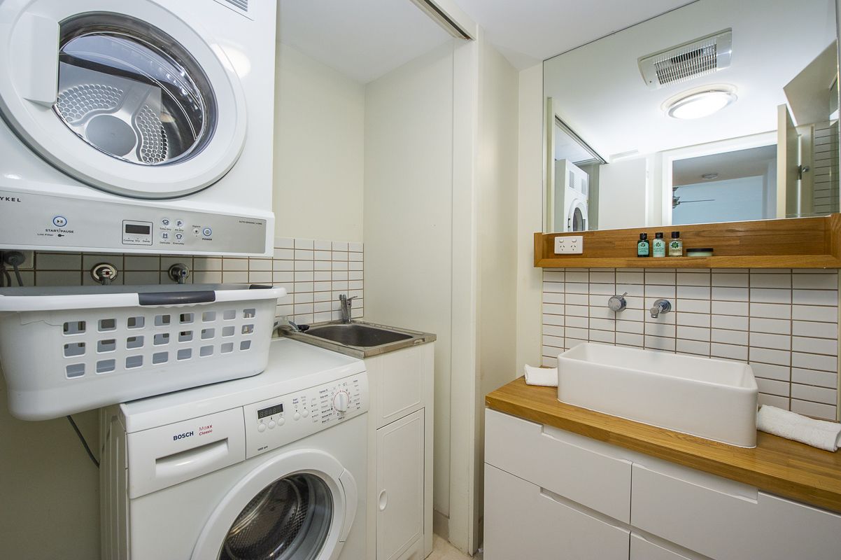A compact laundry area with a washing machine, dryer, and stacked laundry basket.