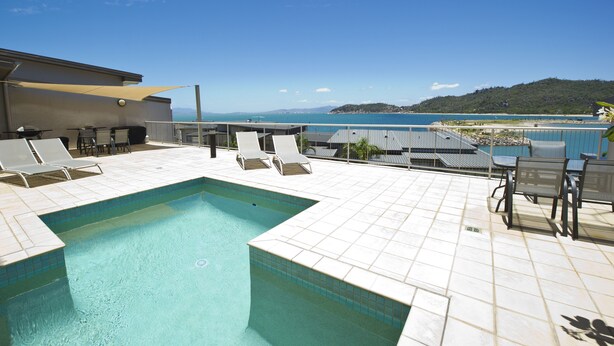 Un espace piscine aménagé sur le toit, avec des chaises longues et une vue sur la mer.