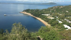 A coastal area with a pier extending into the water, surrounded by greenery and residential buildings. - Reflections Villa 1 (Picnic Bay)
