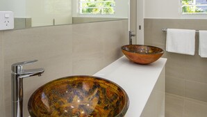 A modern bathroom with a glass bowl sink and a chrome faucet. - Reflections Villa 2 (Picnic Bay)