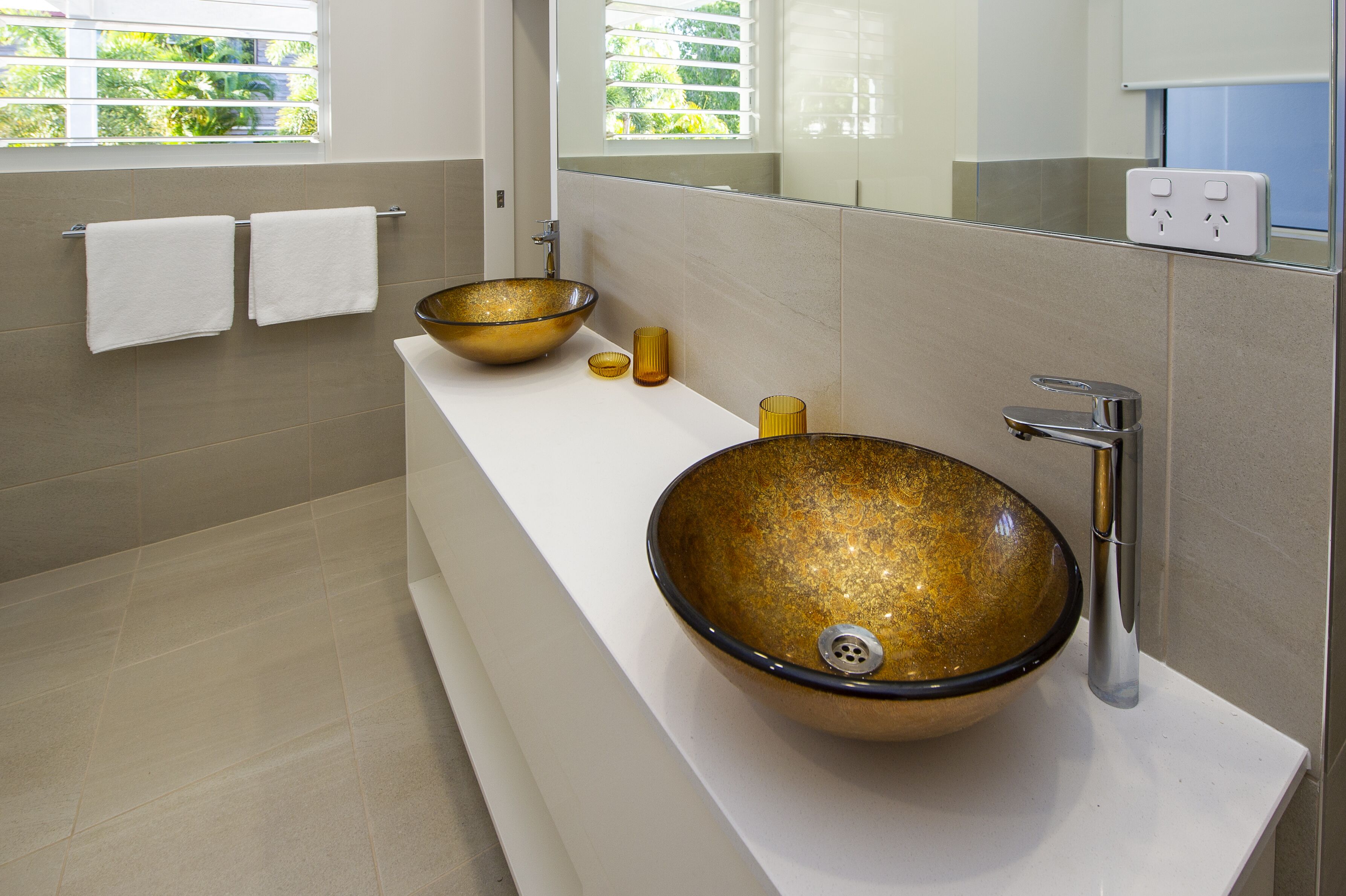 A modern bathroom with a large vessel sink, a mirror, and two towels on a rack.