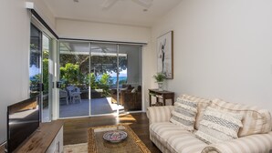 A modern living room with a sofa, a TV, and a wicker coffee table.