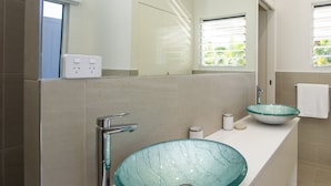 A modern bathroom with a glass bowl sink, a chrome faucet, and a white countertop. - Reflections Villa 4 (Picnic Bay)