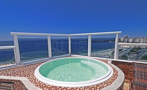 A hot tub with a clear view of the ocean and cityscape.