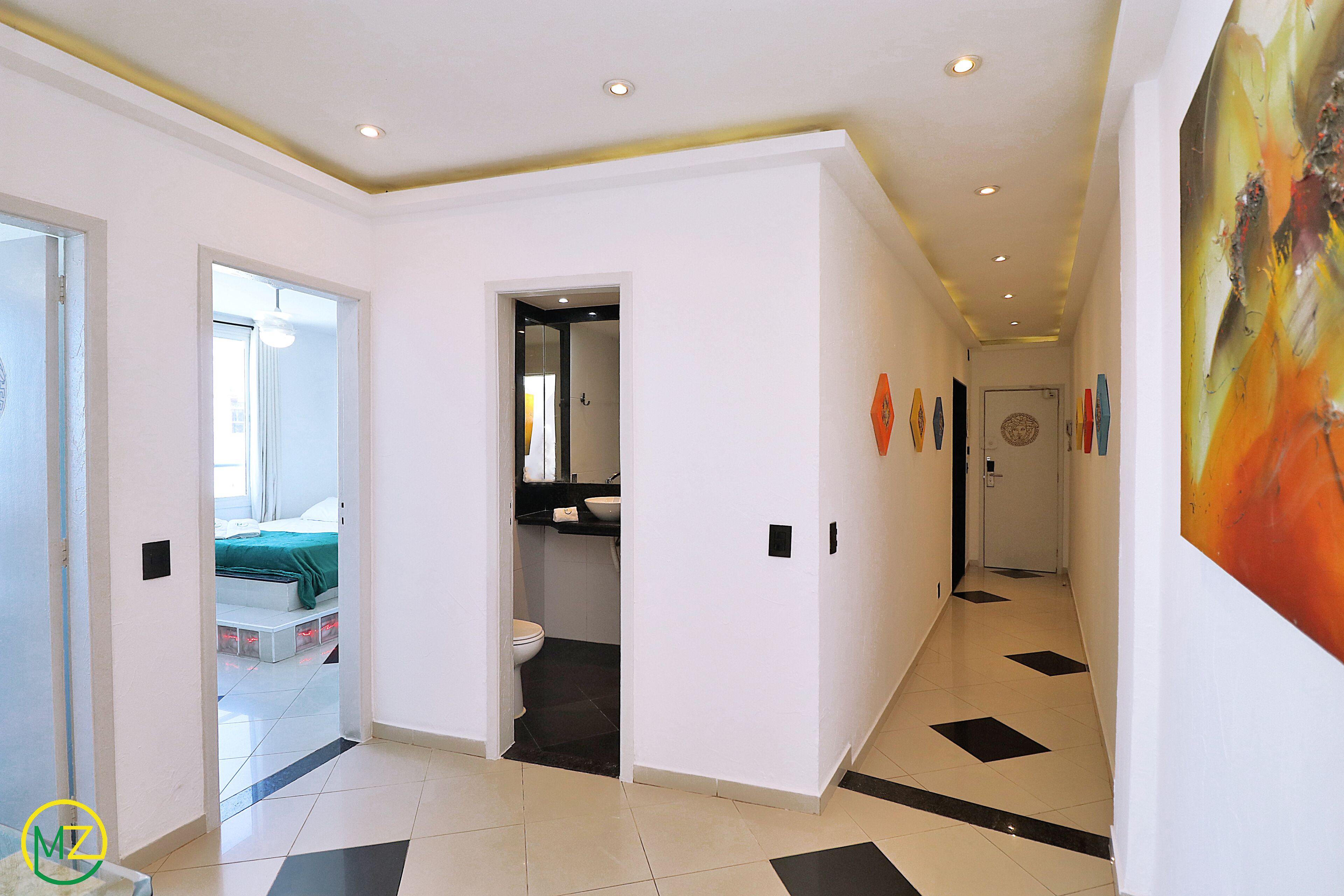 Un pasillo con un baño, una cama y una puerta que da a otra habitación.