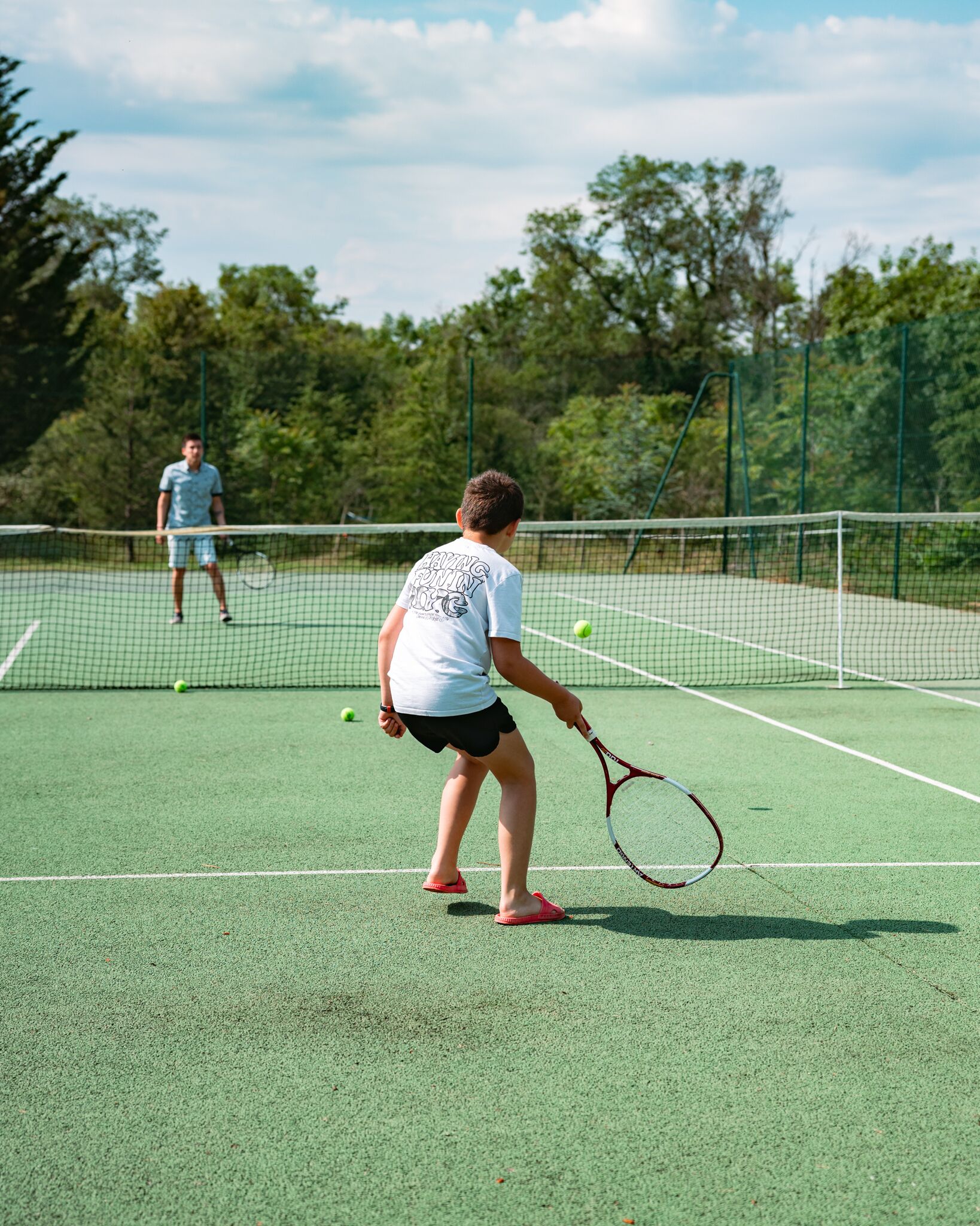 A tennis court with a net in the middle, surrounded by trees.