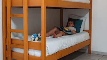 A bunk bed with a ladder, two children, and toys on the floor.