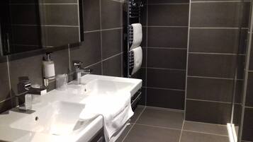 Un baño moderno con dos lavamanos, un espejo grande y un perchero para toallas.