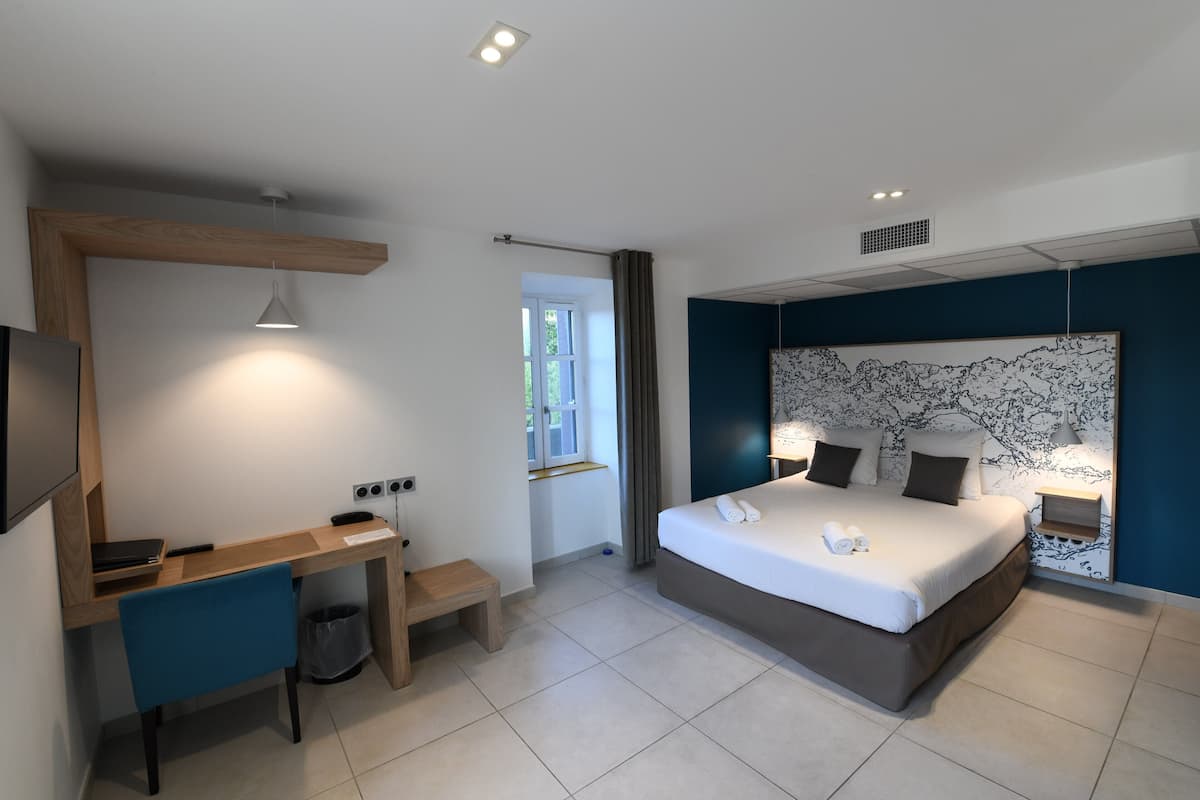Ein modernes Schlafzimmer mit Bett, Schreibtisch, Stuhl und einem großen Fenster.