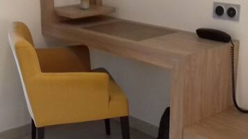 Un escritorio moderno con detalles de madera, una silla amarilla y un pequeño jarrón con flores sobre una estantería.
