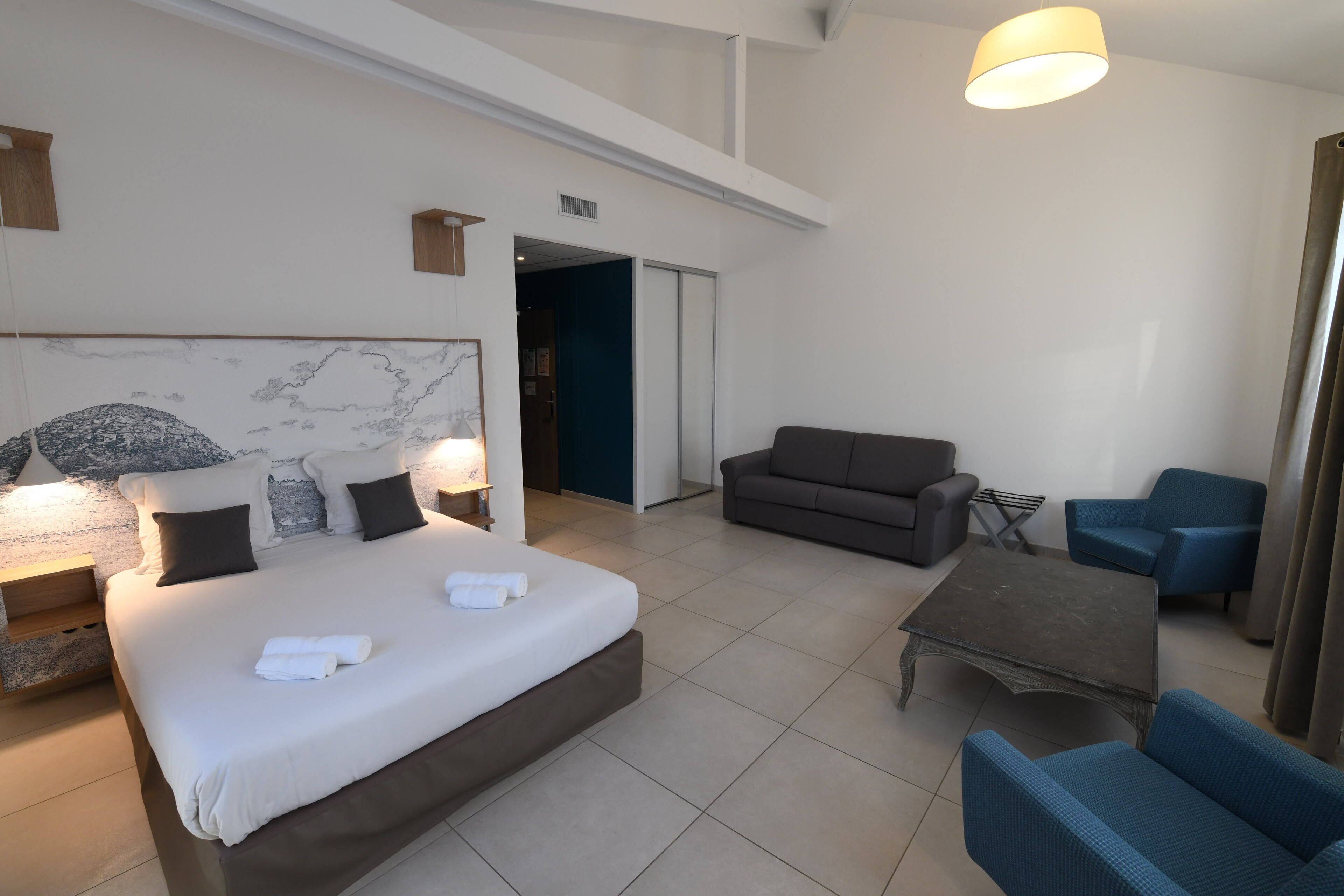 Una habitación de hotel moderna con una cama grande, un sofá, una mesa de centro y un escritorio.