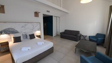 Una habitación de hotel moderna con una cama grande, un sofá, una mesa de centro y un escritorio.