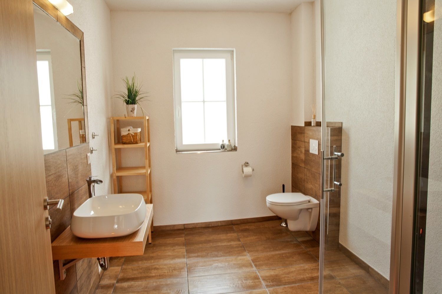 Un baño moderno con un lavamanos grande, inodoro y cabina de ducha de vidrio.