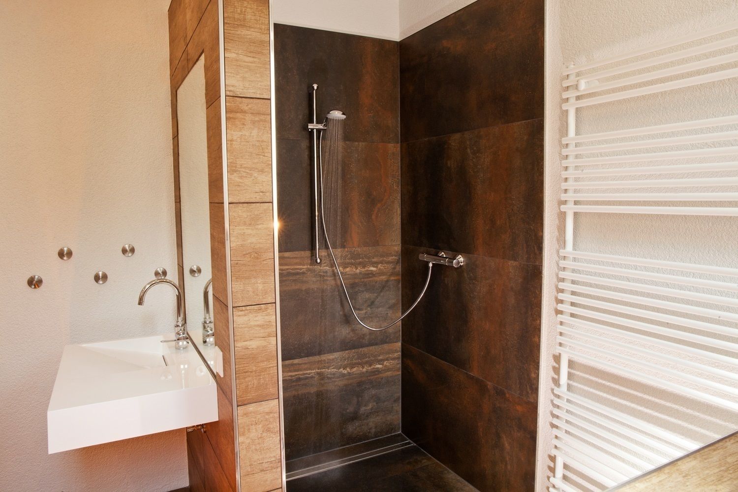 A modern bathroom with a shower, sink, and towel rack.