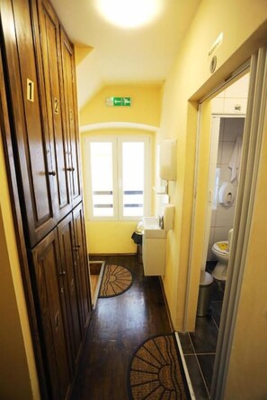 A hallway with wooden cabinets, a door leading to a bathroom, and a small rug on the floor. - Tequila Bar Hostel - Adults Only (Zadar)