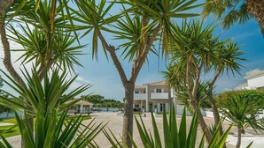 A modern building with a paved courtyard, surrounded by palm trees. - Ostria Luxury Villa (Zakynthos)