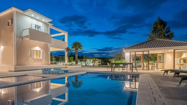 A modern two-story house with a swimming pool, outdoor seating, and a patio area. - Ostria Luxury Villa (Zakynthos)