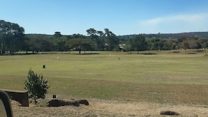 A large, open grassy field with trees and a distant hill. - KaRwizi  (Harare)