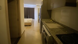 Habitació d'hotel senzilla amb cuineta, llit i bany.