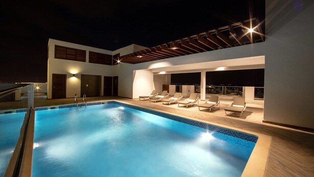 Una piscina al terrat amb gandules i una zona de seients coberta.