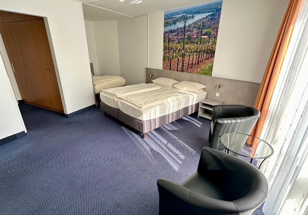 Habitación de hotel con cama, una silla, una mesita y un ventanal con vistas.