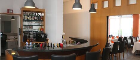 A modern kitchen with a bar area, bar stools, pendant lighting, and a wine rack.