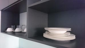 Una cucina con un piano di lavoro nero e una pila di piatti bianchi.