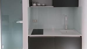Una cucina moderna con mobili scuri, un piano di lavoro bianco e un lavello incassato.