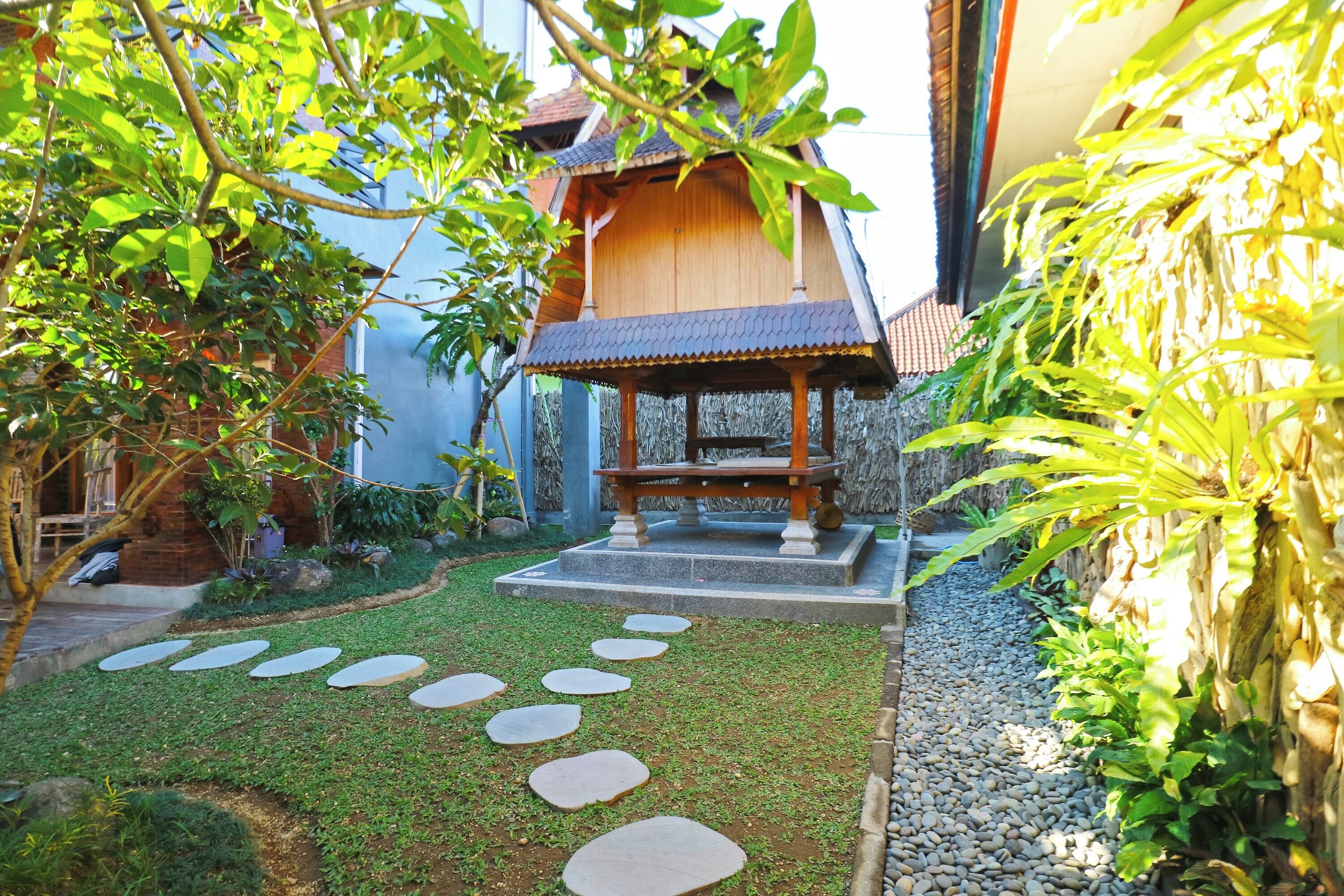 A traditional wooden structure with a tiled roof, surrounded by a well-maintained garden with stepping stones and gravel paths.