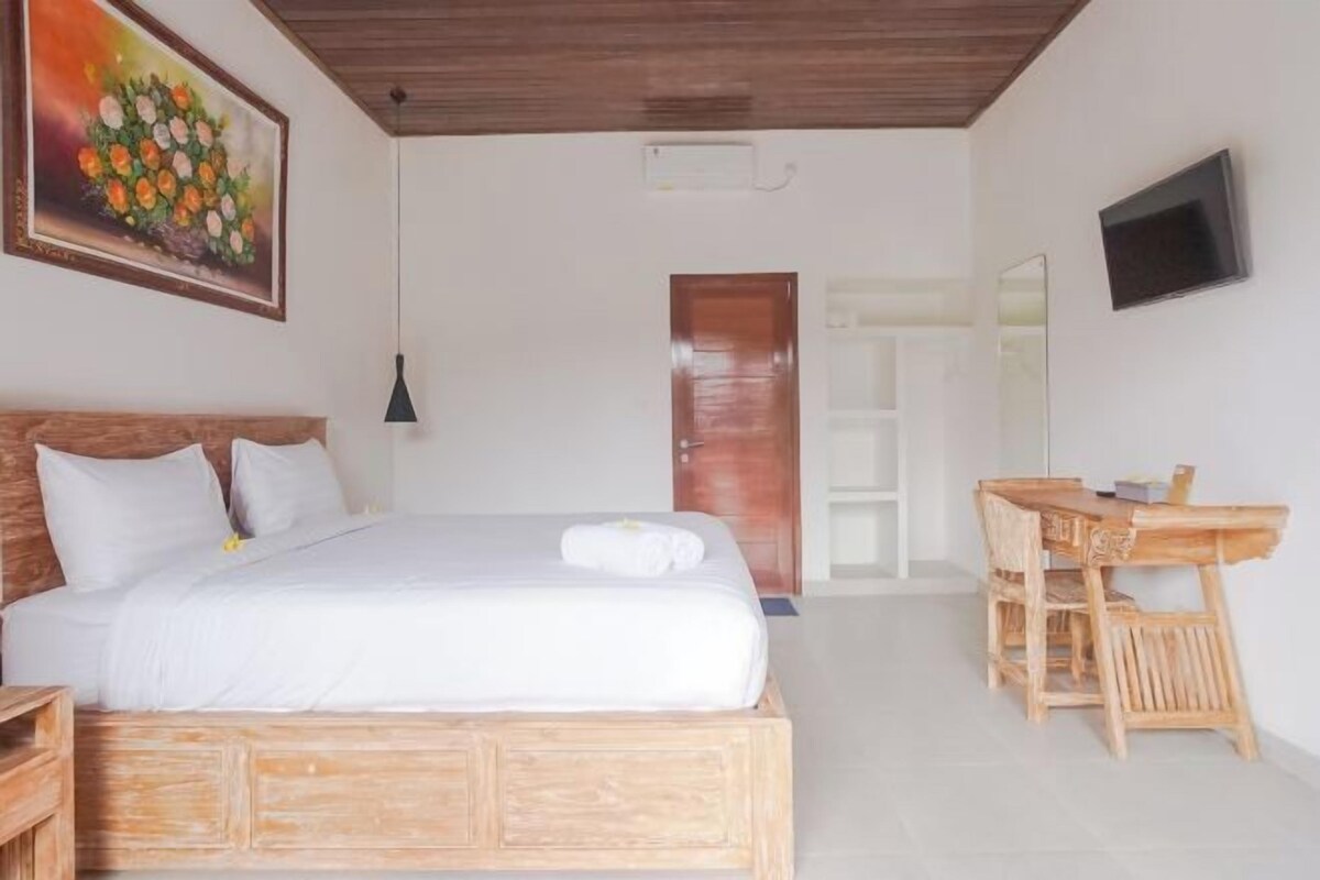 A bedroom with a bed, a desk, and a chair.