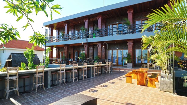 A two-story building with a bar area on the ground floor, outdoor seating, and a pool. - Pondok DD Canggu (Canggu)