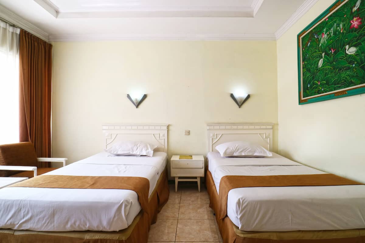 Une chambre d’hôtel avec deux lits, une table de chevet, une chaise et un tableau au mur.