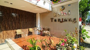 A hotel entrance with a tiled patio, outdoor seating, and potted plants. - Hotel Tanjung (Surabaya)