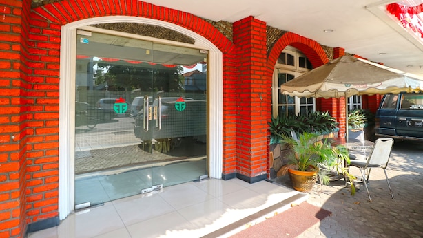 A storefront with a glass door, red brick walls, and a tiled floor. - Hotel Tanjung (Surabaya)