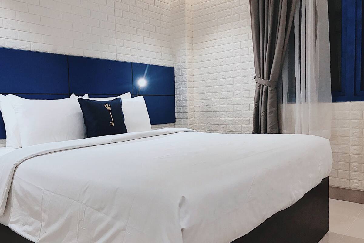 A neatly made bed with white bedding and a dark headboard.