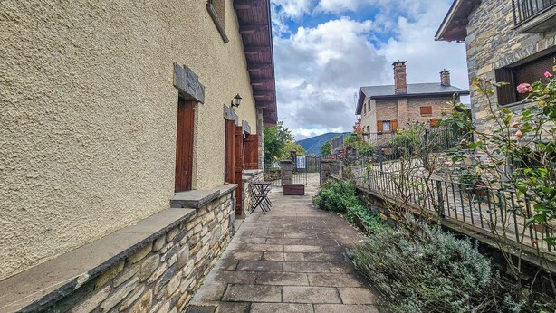 A narrow stone pathway flanked by buildings with wooden shutters and a stone wall. - Apartamentos Gavín Biescas 3000 (Biescas)